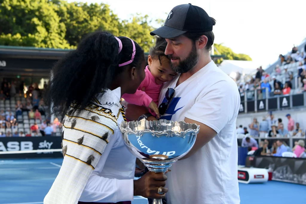 Serena Williams holding a tournament trophy along with her Husband and Daughter